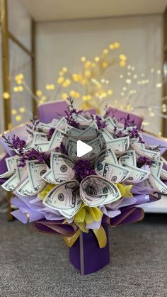 a bouquet made out of money sitting on top of a purple box with yellow flowers