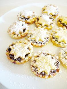 a white plate topped with mini pies covered in powdered sugar