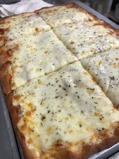 a square pizza sitting on top of a pan covered in cheese