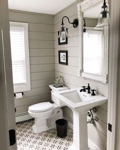 a white toilet sitting next to a sink in a bathroom under a window with shutters