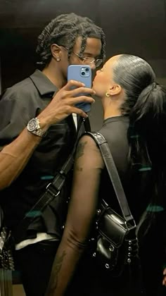 a man and woman kissing while taking a selfie