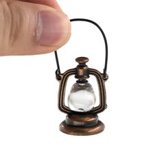 a hand holding an antique style miniature lantern