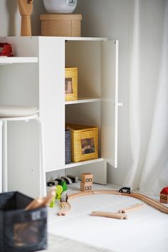 a toy train set sitting on top of a table next to a white shelf filled with toys