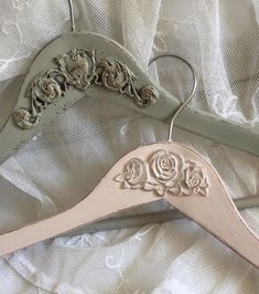 two wooden hangers with roses on them sitting on a white cloth covered bed sheet