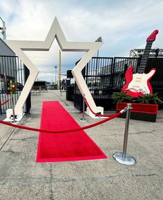 a red carpet with an electric guitar on it next to a white star shaped entrance