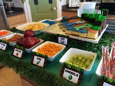 a table filled with lots of food on top of a green table cloth covered in grass