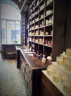 an old fashioned kitchen with lots of shelves and jars on the counter top, in front of a large window