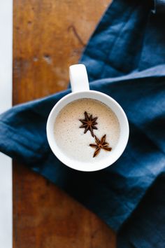 an overhead view of a cup of coffee with star anise on the top and blue napkin