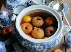 a pot filled with fruit sitting on top of a wooden table next to other dishes