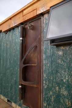 an old door is open on the side of a green building with a flat screen tv mounted to it's wall