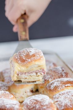 powdered sugar covered pastries are being held by a person using a pastry knife