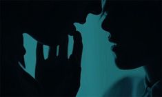 two people standing next to each other with their hands on their faces in the dark