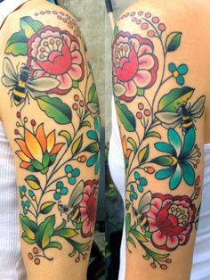 two women with tattoos on their arms and one is showing off her colorful flowered arm