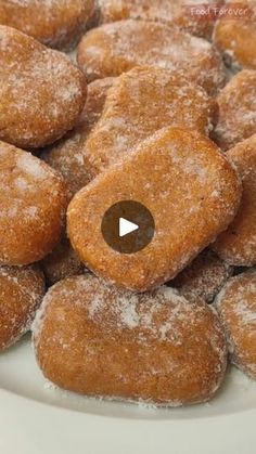 powdered sugar donuts on a plate with a video play button in the middle