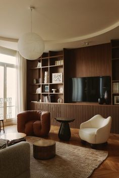 a living room filled with furniture and a flat screen tv mounted on a wall next to a window