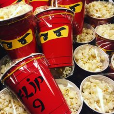 red cups filled with popcorn sitting on top of a table next to other plastic containers