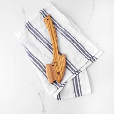 two wooden utensils sitting on top of a white and blue striped napkins