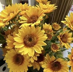 a vase filled with yellow sunflowers on top of a table