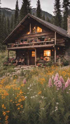 a log cabin with flowers in the foreground