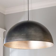 a large metal light hanging from the ceiling in a room with white walls and windows