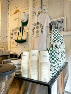 stacks of white paper cups sitting on top of a metal counter in a restaurant or bar