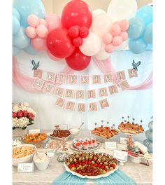 a table topped with lots of food and balloons