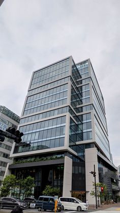 an office building with many windows and cars parked on the street in front of it