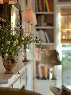 a vase filled with flowers sitting on top of a white counter next to a lamp