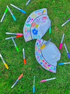 two umbrellas are laying on the grass with crayons all over them