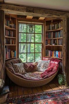 a couch in front of a window with bookshelves and rugs on the floor