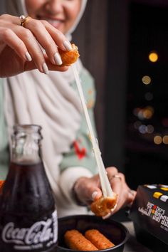 a woman in hijab is eating some food with a spoon and soda on the table