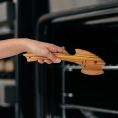 a person holding a wooden object in front of an oven