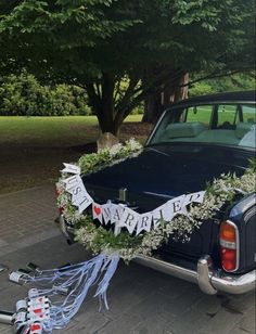 an old black car is decorated with flowers and garlands for a wedding ceremony at the park