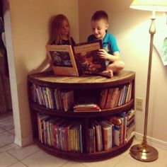 two children are sitting on a bookshelf and looking at the book they're reading