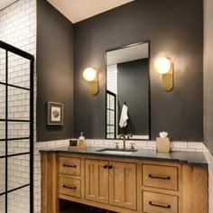 a bathroom with two sinks, mirrors and lights on the side of the vanity area