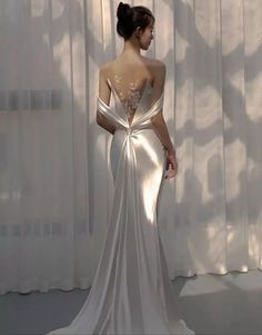 the back of a woman's wedding dress in front of a curtained window