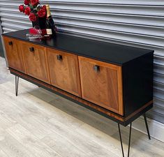 a black and wood sideboard with flowers on top