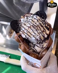 an ice cream sundae is being held by a gloved hand