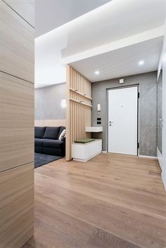 an empty living room with wood floors and white walls, along with a black couch