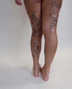 a woman's legs with tattoos on them and no shoes in front of her