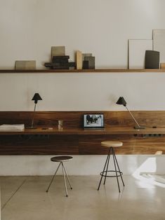 a desk with two stools in front of it and some books on the shelf