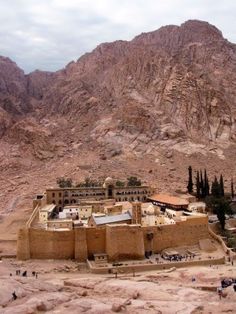 a large building in the middle of a desert with mountains in the backgroud