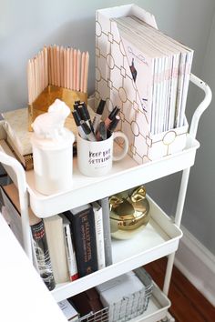 a white shelf with books, cups and other items on it