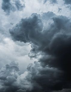 an airplane flying in the sky with dark clouds behind it and one plane on the ground