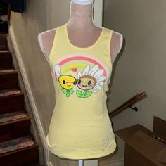 Tokidoki Rare Vintage Tank Top, Ribbed Style, Sizes Small, Large And Xl Available, Pale Yellow Color, Front Features Large Graphic Print Of Flower Characters And Rainbow, Bottom Features Tkdk Heart And Crossbones Logo In Rhinestones, Back Features Small Graphic Print Of Flower Character And Tkdk Logo, Brand New With Tags, Very Rare And Hard To Find, Purchased From Australia! Fun Yellow Sleeveless Top, Yellow Playful Fitted Tops, Playful Fitted Yellow Tops, Fitted Playful Yellow Tops, Fitted Yellow Playful Tops, Kawaii Sleeveless Tops For Spring, Spring Kawaii Sleeveless Tops, Cute Fitted Tank Top, Fitted Fun Tank Top