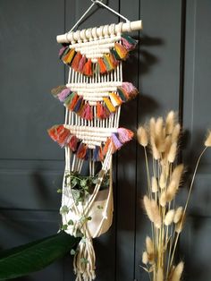 a plant with some flowers in it next to a wall hanging