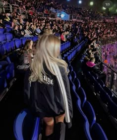 a woman standing in front of an audience at a sporting event with her back to the camera