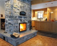 a stone fireplace in the middle of a living room with wood flooring and an open fire place