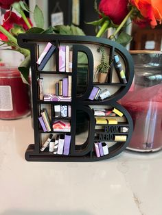 the letter b is made out of books and magazines on a table next to flowers