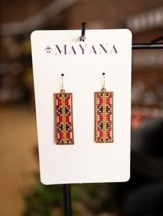 a pair of earrings is displayed on a display stand in a retail store, with the name mayona printed on it